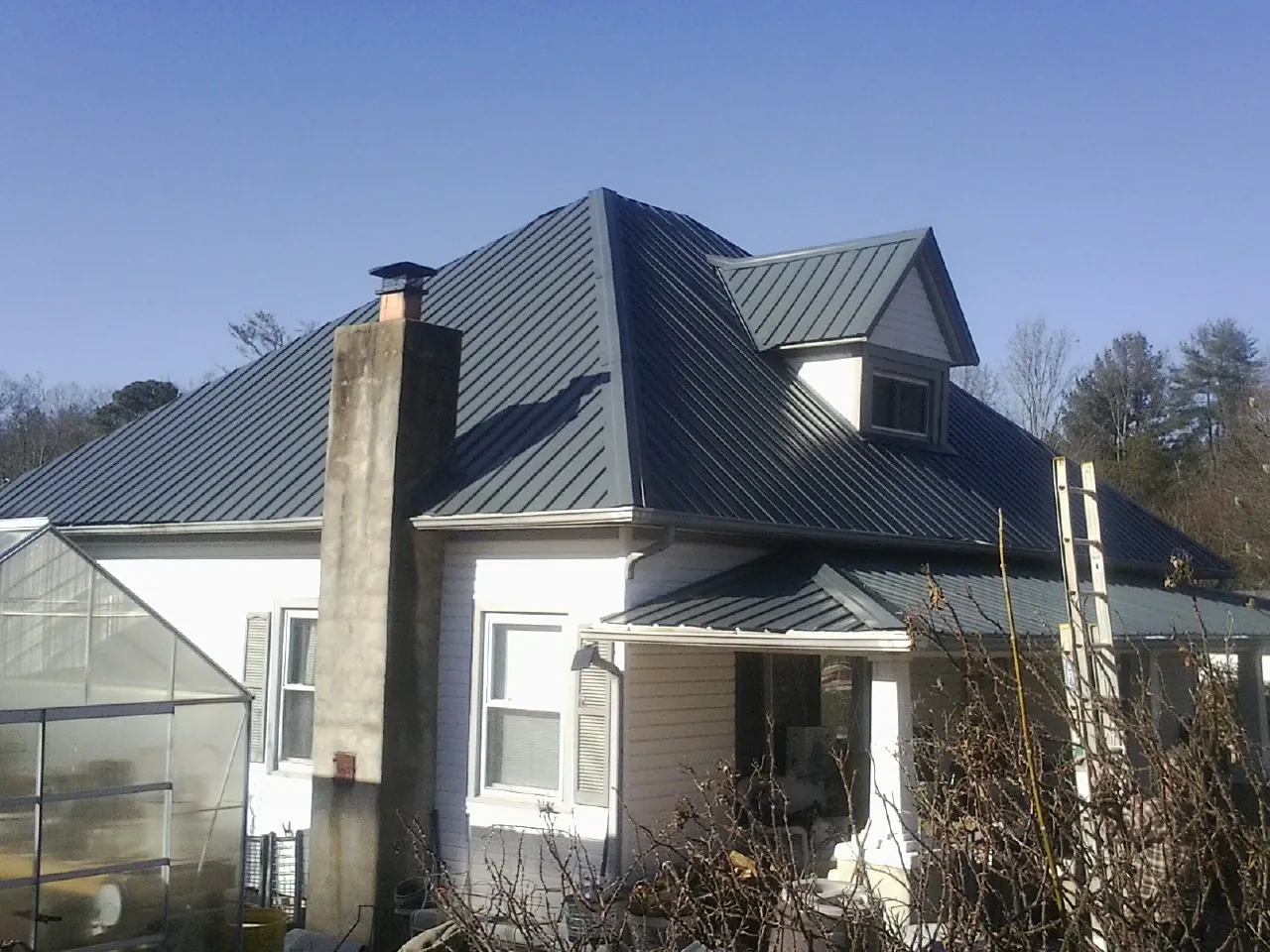 Dark blue standing seam metal roof on a white farmhouse with dormer — Slate & Tile Roof Repair by Roofing Brothers in Illiopolis