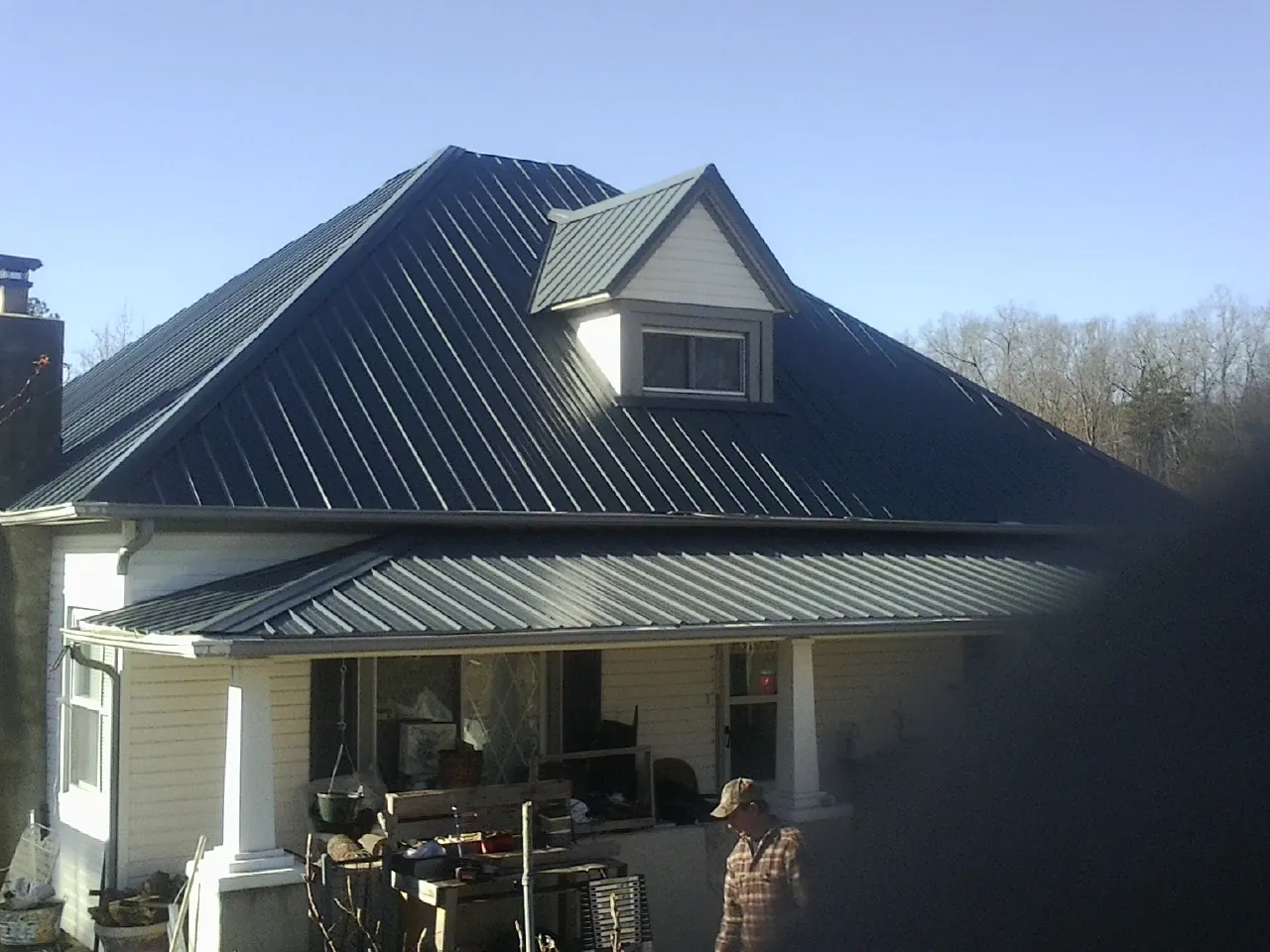 Dark blue standing seam metal roof with a dormer above a front porch in Illiopolis
