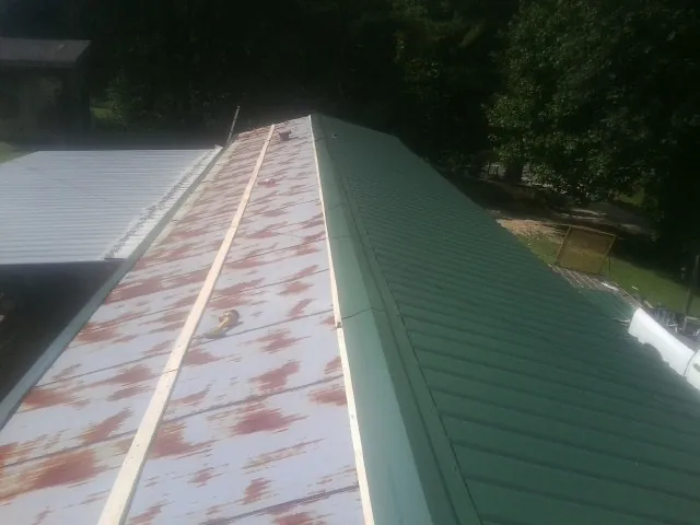Old rusted panels beside newly installed green metal roofing — Wind Damage Roof Repair by Roofing Brothers in Illiopolis
