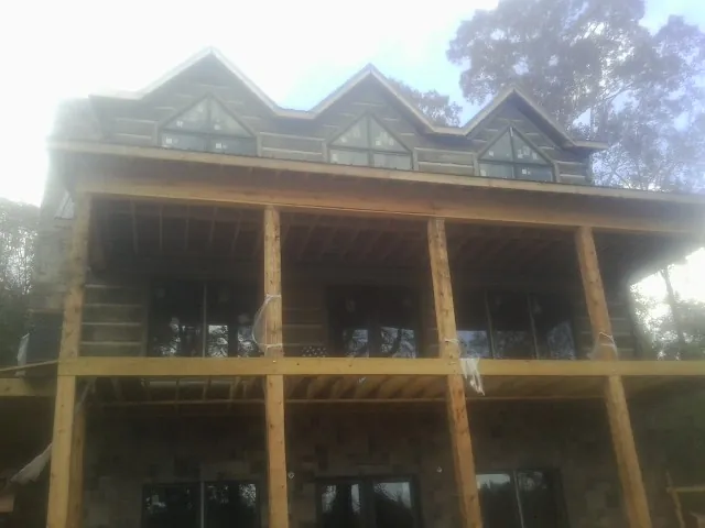 Dormers and porch framing on a large log home under construction — Roof Coating work by our crew in Illiopolis
