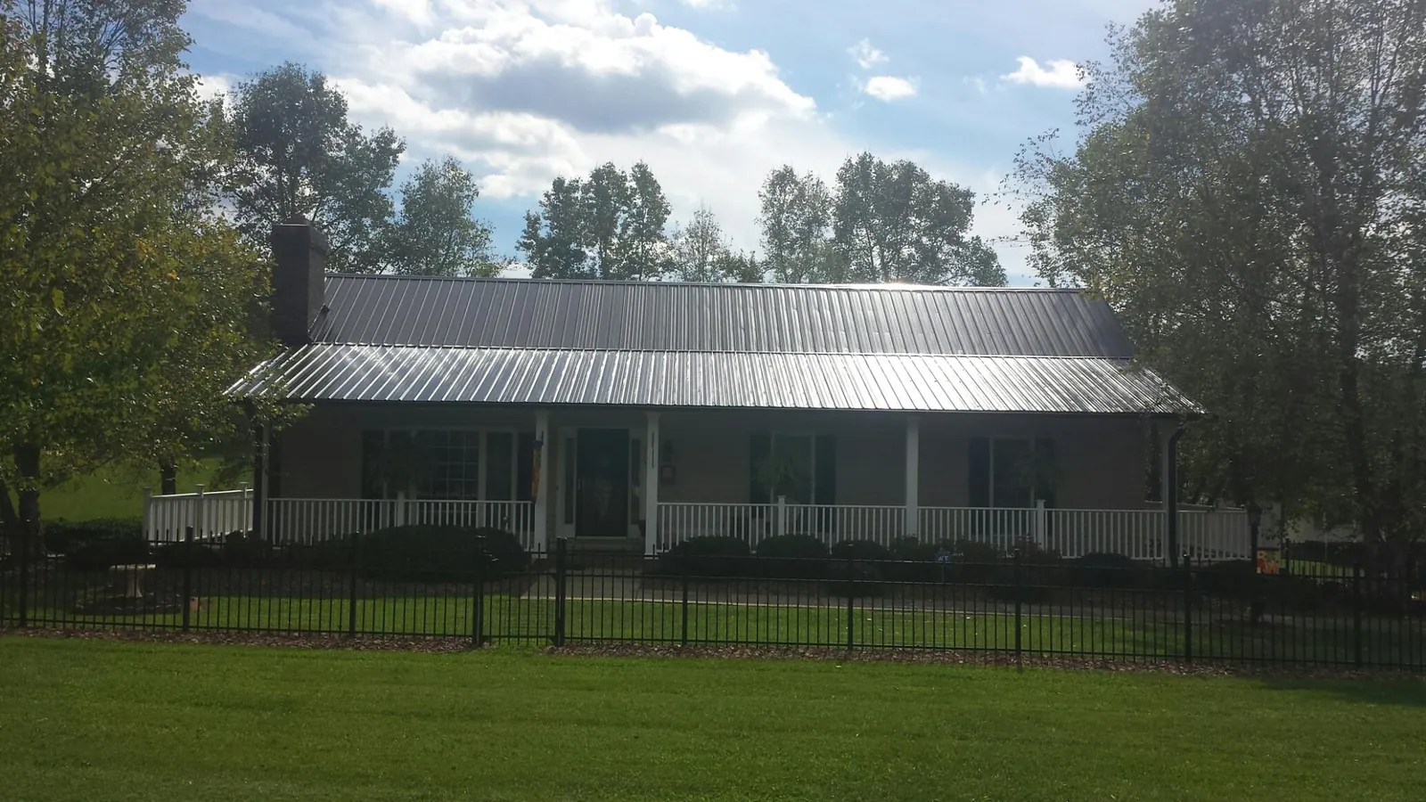 Gray metal roof on a brick ranch with a full width front porch — Gutter Guard Installation work by our crew in Illiopolis