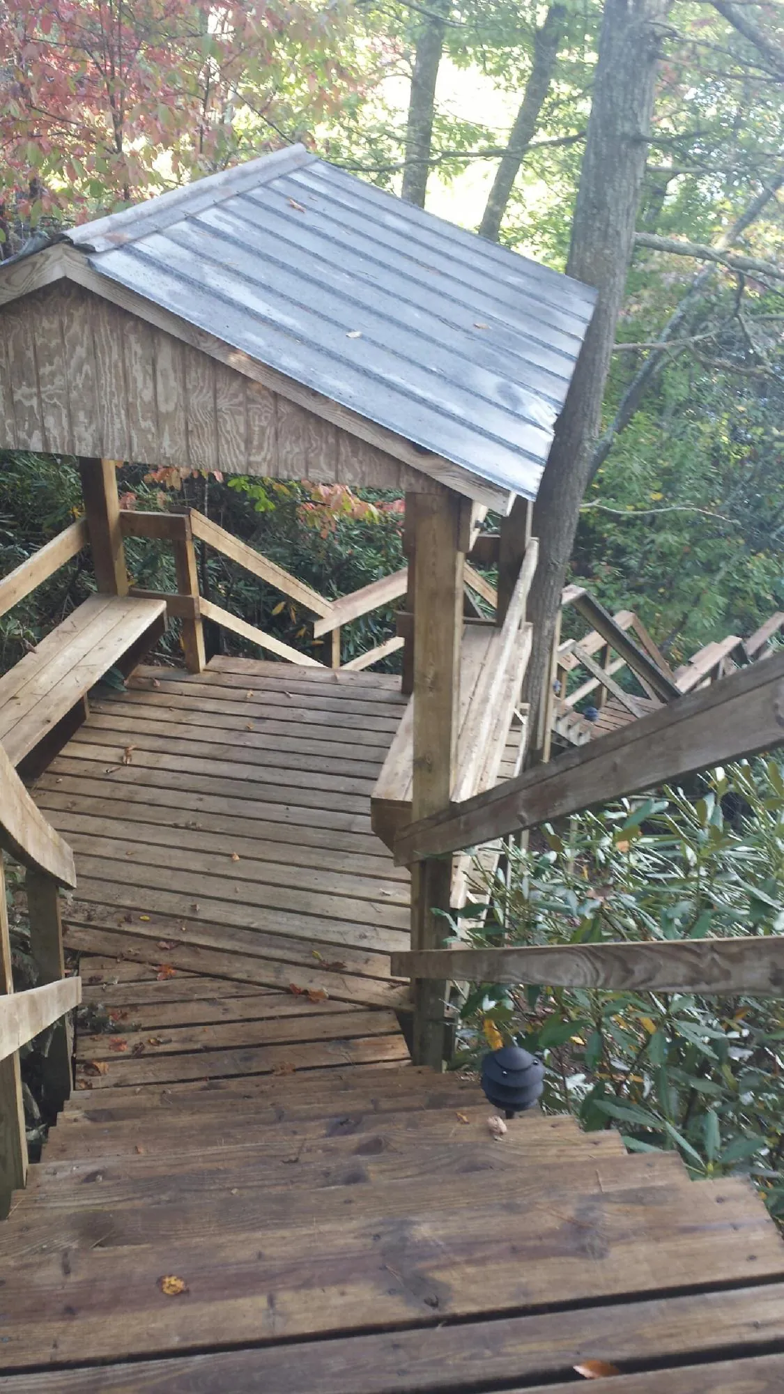 Metal roofed shelter over wooden steps on a wooded walkway — Skylight Repair & Installation work by our crew in Illiopolis