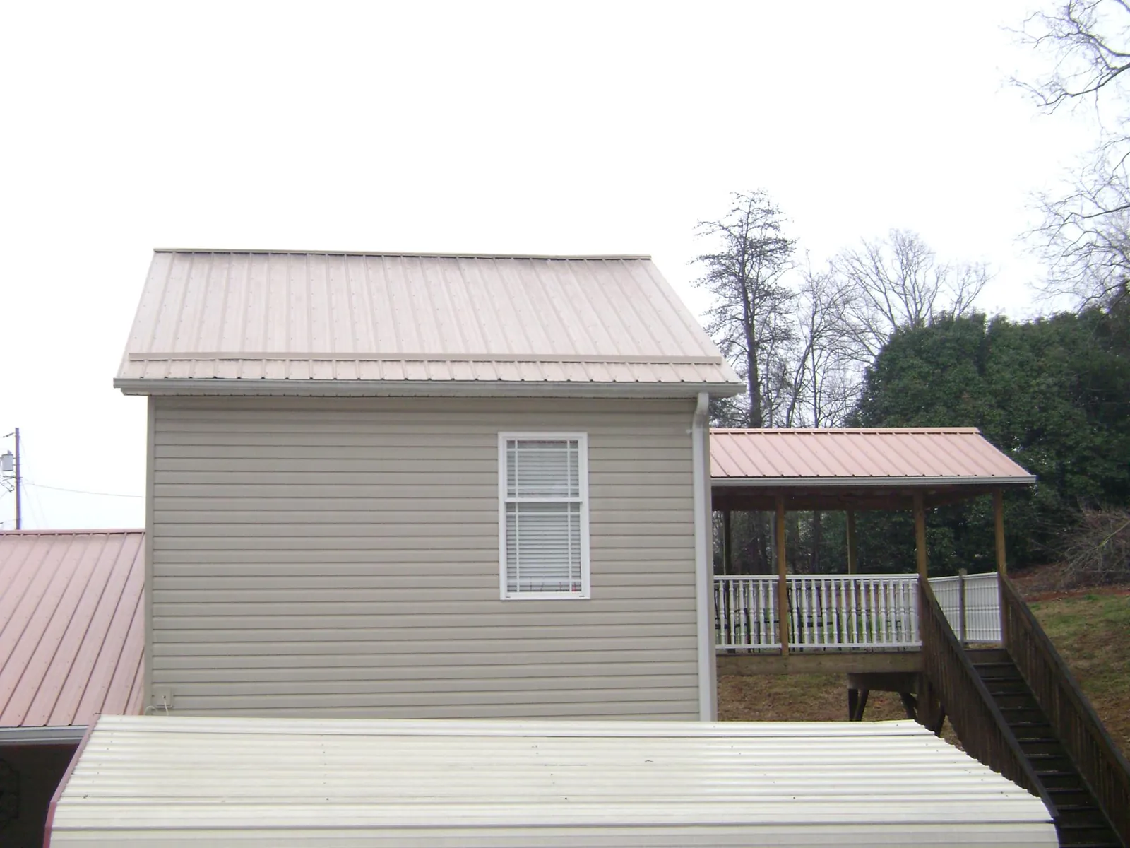 Tan metal roofs on a two story addition and attached porch, from a Roof Replacement job in Illiopolis
