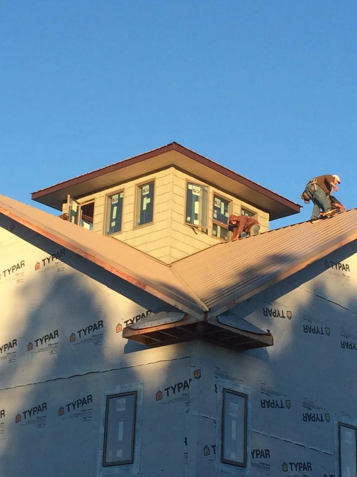 Roofers working around a rooftop cupola on a new metal roof at sunset — Roof Waterproofing in Illiopolis by Roofing Brothers